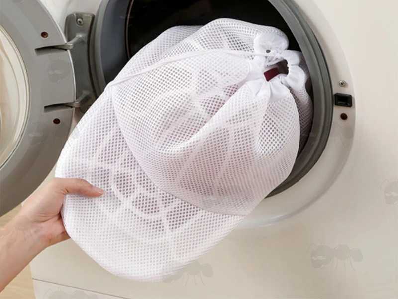 White Netting Washing Machine Bag with White Plastic Cage for Baseball Cap Cleaning, Shown Going into Washing Machine