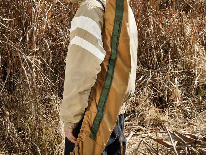 Brown Coloured Elastic Rifle Cover Slip Bag with Elasticated Rim for Gun with Silencer, Scope and Bipod Fitted, Being Carried Over Shoulder