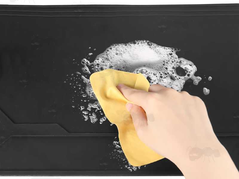 Black Coloured Rubber Rifle / Shotgun Sized Cleaning / Maintenance Mat with Moulded Compartments for Parts and Magnetic Section, Shown Being Washer