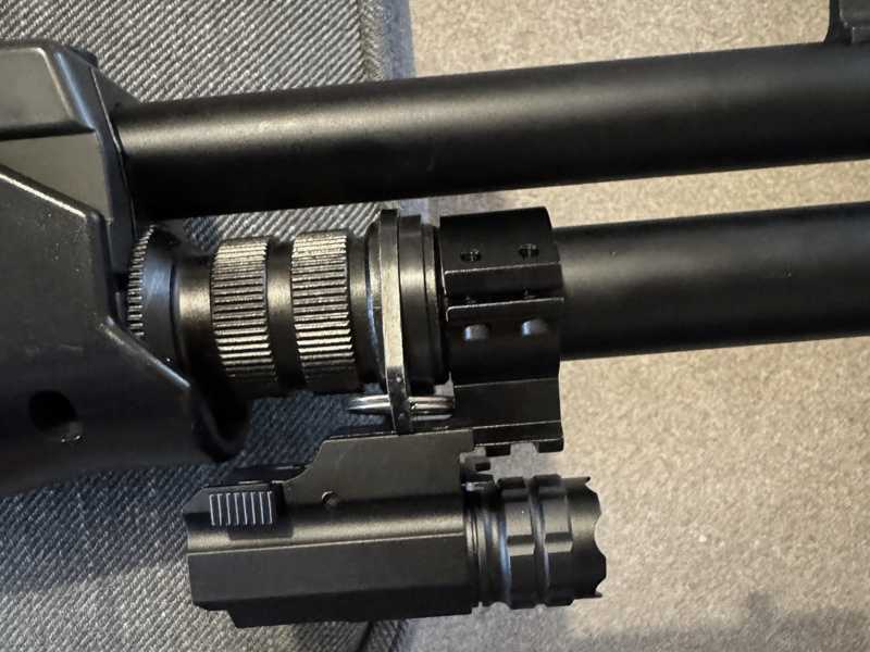 Black Aluminium Body Compact LED Tactical Torch Unit with View of Quick Fitting Lever The Base Weaver / Picatinny Rail Mount Fitting, Shown Fitted to an Airsoft Shotgun Magazine Tube